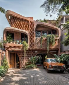 an old car parked in front of a brick building with plants growing on the balconies