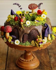 a cake decorated with mushrooms and flowers on top of a wooden table