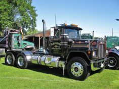 a large semi truck parked on top of a lush green field