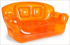 an orange plastic chair that looks like it has been made out of glass and is shaped to look like a couch