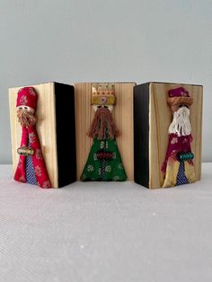 three small wooden dolls are sitting in the same box as one is wearing a crown