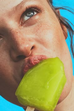 a close up of a person eating a green piece of food with a toothpick in their mouth