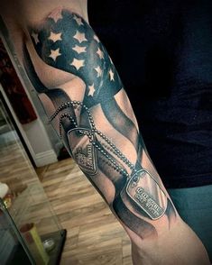 a man's arm with an american flag and chains on it, holding a beer bottle