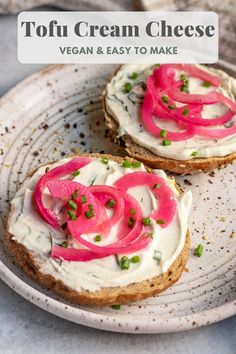 two pieces of bread with cream cheese and red onions on them sitting on a plate