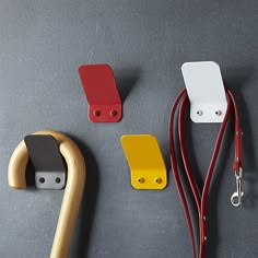 three different colored handles and cords on a gray surface with one red, the other yellow