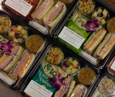 four plastic containers filled with different types of sandwiches and salads on top of a table