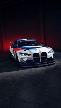 a white and blue sports car parked in a dark area with red lights behind it