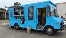 a blue food truck is parked in front of a building and has its door open