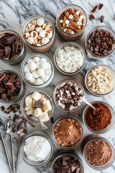 many different types of food in small bowls on a marble counter top with spoons