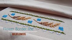 a close up of a flower border line on a white cloth with blue and yellow flowers