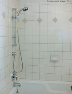 a white tiled bathroom with a tub and shower head in the bathtub is shown