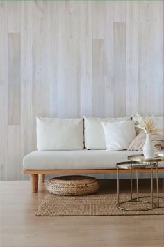 a white couch sitting on top of a wooden floor next to a table with two vases