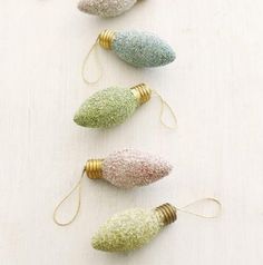 four christmas ornaments are lined up on a white surface with gold, silver and green decorations