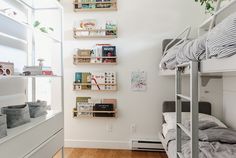 a bedroom with bunk beds and shelves filled with books on the wall next to it