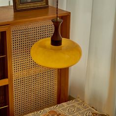 a yellow lamp hanging from the ceiling next to a table with a basket on it