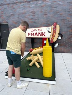 a man standing in front of a fake hot dog stand