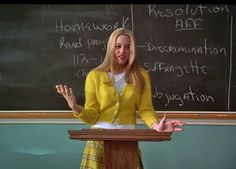 a woman standing at a podium in front of a chalkboard