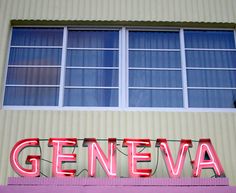 a large neon sign that says geneva on the side of a building next to a window