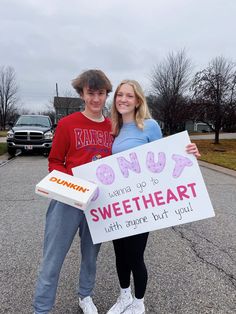 two people standing in the street holding a sign