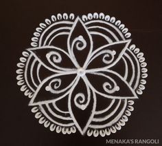 an intricately designed design on a black surface with white chalk paste in the shape of a flower