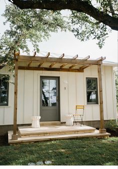 a small white house with two chairs on the porch