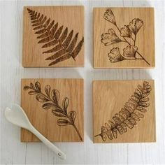 four wooden coasters with different types of leaves and flowers on them next to a spoon