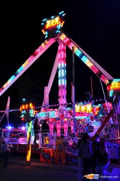 a carnival ride lit up at night with people walking around