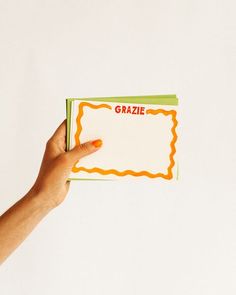 a person's hand holding up a card with the word grazie written on it