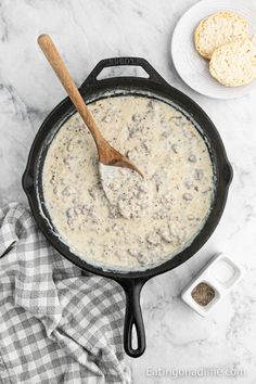 a cast iron skillet filled with cream cheese and biscuits on a marble counter top