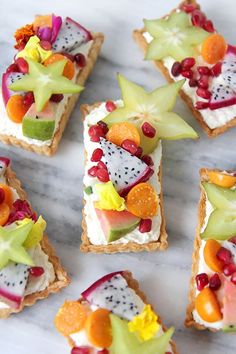 small crackers with fruit on them are arranged on a marble countertop, ready to be eaten