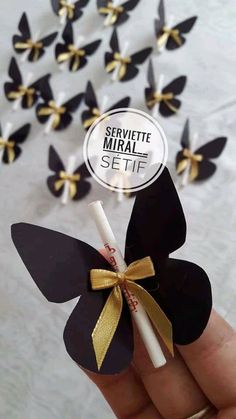 a hand holding a small black and gold paper flower with a white stick sticking out of it