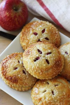 several small pastries on a plate with an apple in the background