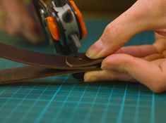 someone cutting leather with scissors on a table