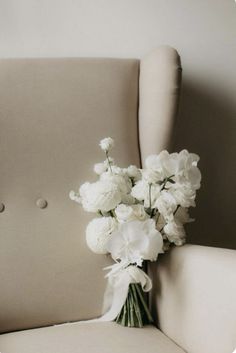 a bouquet of white flowers sitting on top of a chair in front of a wall