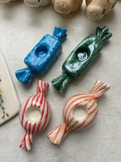 four ceramic fish sitting on top of a table next to a plate and vases