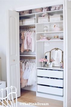 a white closet filled with baby clothes next to a dresser