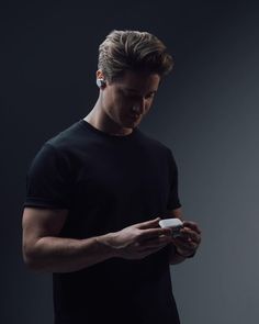 a man in black shirt holding a cell phone and looking down at his wristband