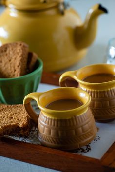 two mugs and some bread on a tray