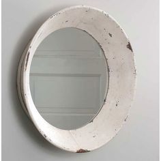 an old white round mirror hanging on the wall