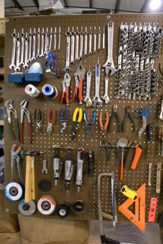 there are many tools hanging on the pegboard in this workshop area, including wrenches and pliers