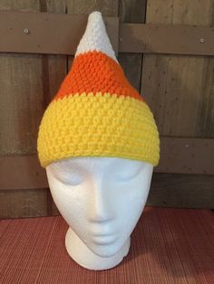 a white mannequin head wearing an orange and yellow knitted hat