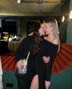 two women are kissing each other at a party