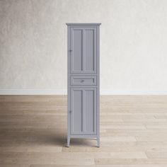 a tall gray cabinet sitting on top of a hard wood floor next to a wall