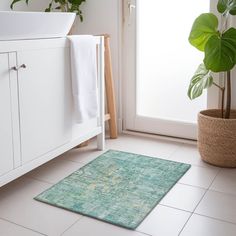 a bathroom with a green rug on the floor next to a white sink and potted plant