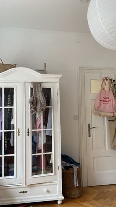 a white armoire sitting on top of a hard wood floor