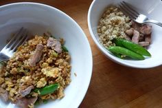 two bowls filled with rice and meat on top of a wooden table next to a fork