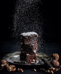 a stack of brownies sitting on top of a plate covered in powdered sugar