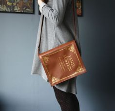 a woman is holding a brown book in her hand