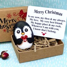 a penguin figurine sitting in a box with a merry christmas card