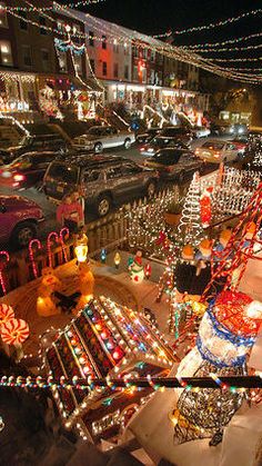 christmas lights and decorations are on display in the city street at night, with cars parked nearby